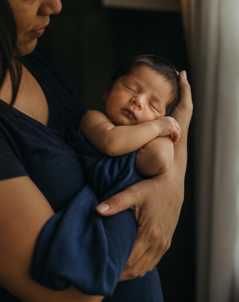 A newborn asleep in a parent's arms